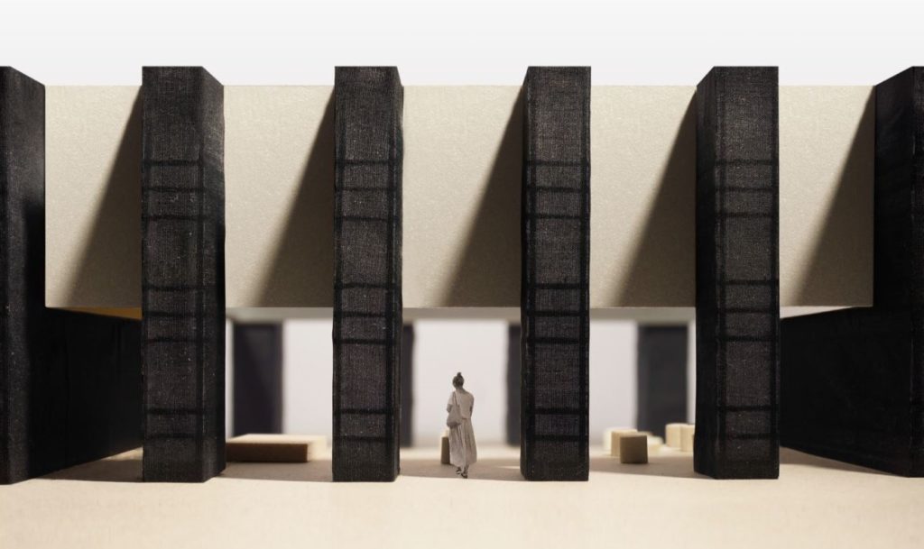 Image of an architectural model with columns and a female figure. 